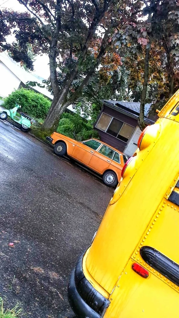 Active micro-mobility scooter alongside school transit on rainy street